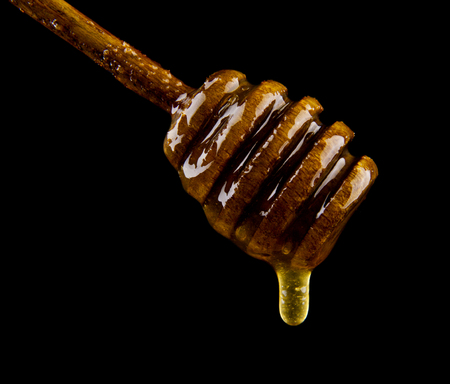 Honey on wooden spoon isolated on blackの写真素材