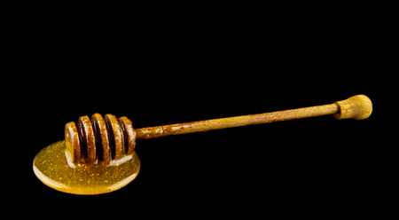 Honey on wooden spoon isolated on blackの写真素材