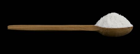 Salt in a wooden spoon isolated on a black background close-up. Macro, full focus.の写真素材