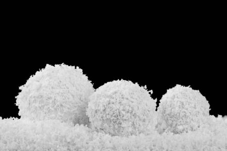 Snowball in a heap of snow Isolated on a black background close-up. Background for christmas and new...