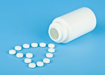 White pills in the form of a heart on a blue background close-up.の写真素材