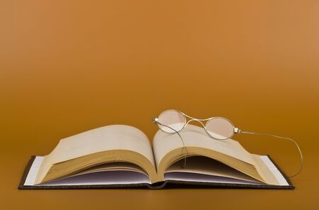 Book and glasses on a brown background close-up.の写真素材