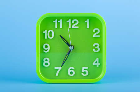 Green clock alarm clock on a blue background close-up.の写真素材