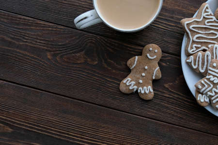 Gingerbread cookies and a cup of coffee on a brown wooden texture backgroundの写真素材