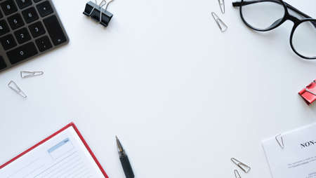 Flatlay with office items and place for text. Layout on a white background. Glasses, keyboard, pen, paper clips, diary, work papersの写真素材