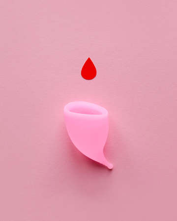 Pink menstrual cup and drop of blood on a pink backgroundの写真素材