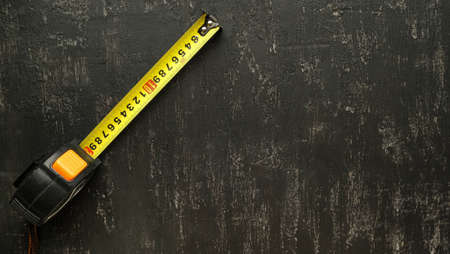 Construction tape measure on a textural black backgroundの写真素材