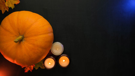 Composition of pumpkins, autumn leaves and burning candles on a black background with space for textの写真素材