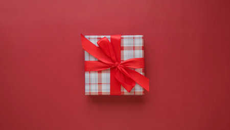 Square gift box with a red bow on a red background top viewの写真素材