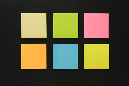 Six multi-colored blank note paper on a black backgroundの写真素材