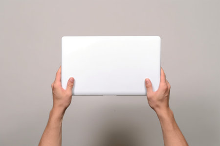 Blank closed laptop in a male handsの素材