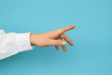 A hand in a white shirt points or touch with a finger on a blue backgroundの写真素材