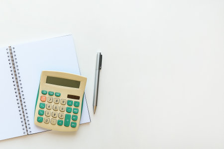 Flat lay with a blank spiral note, calculator and pen