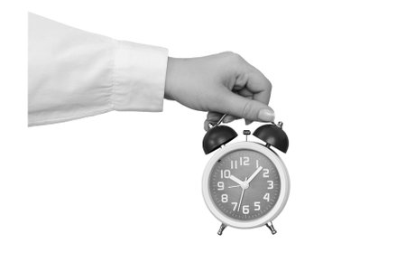 Black and white hand holding a classic alarm clock isolated on white background - element for...