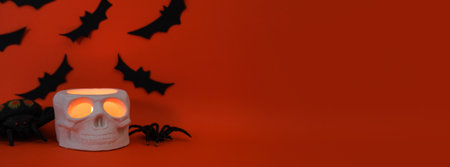 Halloween composition with a skull candle, bats and place for text on dark orange backgroundの写真素材