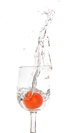 Juicy small cherry tomato dropped in water from glass on white backgroundの写真素材