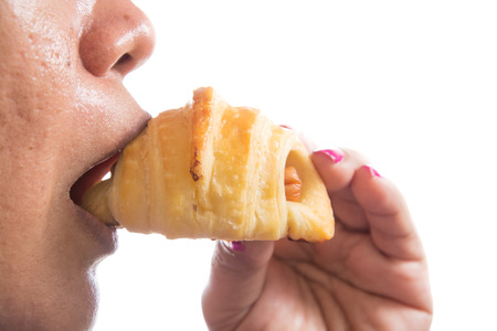 woman  eating croissant with hotdog isolated on white backgroundの写真素材