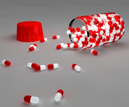 Spilled red pills and bottle on gray backgroundの写真素材