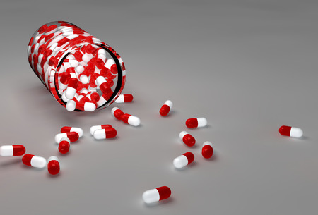 Spilled red pills and bottle on gray backgroundの写真素材