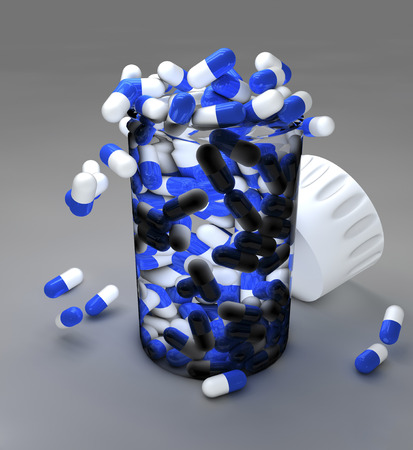 Spilled blue pills and bottle on gray backgroundの写真素材
