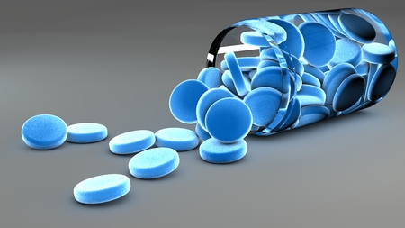 Spilled blue pills and bottle on gray backgroundの写真素材