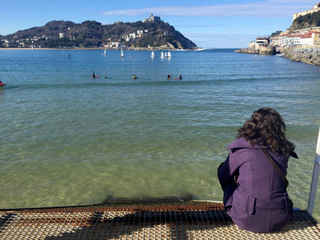 A girl sitting on the pier of Donostia-San Sebastian, Basque Country, City, Spain. The La Concha beach, panoramic view. 28/01/2017のeditorial素材