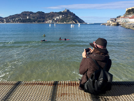 A girl sitting on the pier of Donostia-San Sebastian, Basque Country, City, Spain. The La Concha beach, panoramic view. 28/01/2017のeditorial素材