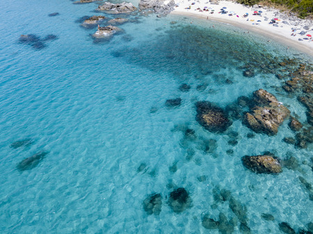 Aerial view of the rocks on the sea. Overview of seabed seen from above, transparent water. Swimmers, bathers floating on the waterの写真素材