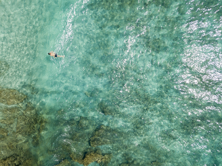 Aerial view of the rocks on the sea. Overview of seabed seen from above, transparent water. Swimmers, bathers floating on the waterの写真素材