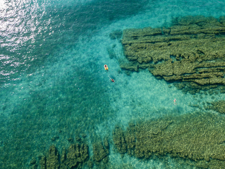 Aerial view of a canoe in the water floating on a transparent sea. Bathers at sea. Zambrone, Calabria, Italy. Diving relaxation and summer vacations. Italian coasts, beaches and rocks.の写真素材