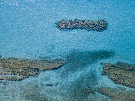 Aerial view of a canoe in the water floating on a transparent sea. Bathers at sea. Zambrone, Calabria, Italy. Diving relaxation and summer vacations. Italian coasts, beaches and rocks.の写真素材