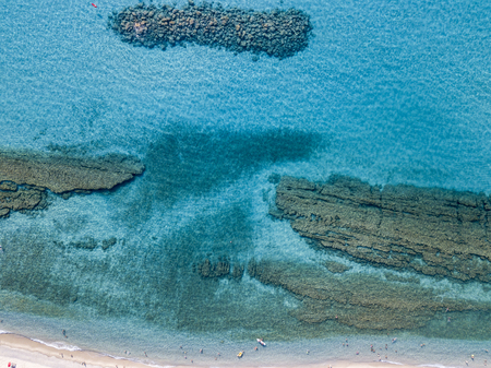 Aerial view of a canoe in the water floating on a transparent sea. Bathers at sea. Zambrone, Calabria, Italy. Diving relaxation and summer vacations. Italian coasts, beaches and rocks.の写真素材