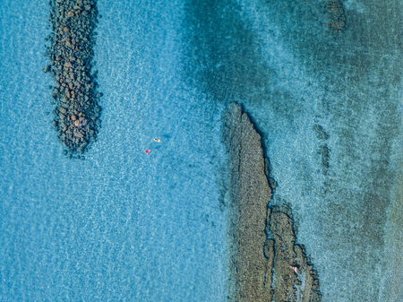 Aerial view of a canoe in the water floating on a transparent sea. Bathers at sea. Zambrone, Calabria, Italy. Diving relaxation and summer vacations. Italian coasts, beaches and rocks.の写真素材