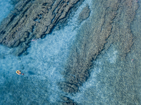 Aerial view of a canoe in the water floating on a transparent sea. Bathers at sea. Zambrone, Calabria, Italy. Diving relaxation and summer vacations. Italian coasts, beaches and rocks.の写真素材