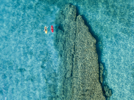 Aerial view of a canoe in the water floating on a transparent sea. Bathers at sea. Zambrone, Calabria, Italy. Diving relaxation and summer vacations. Italian coasts, beaches and rocks.の写真素材
