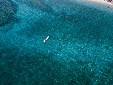 Aerial view of a canoe in the water floating on a transparent sea. Bathers at sea. Zambrone, Calabria, Italy. Diving relaxation and summer vacations. Italian coasts, beaches and rocksの写真素材