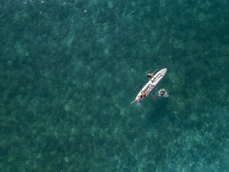 Aerial view of a canoe in the water floating on a transparent sea. Bathers at sea. Zambrone, Calabria, Italy. Diving relaxation and summer vacations. Italian coasts, beaches and rocks.の写真素材
