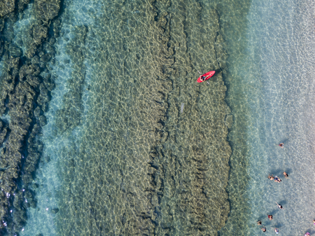 Aerial view of a canoe in the water floating on a transparent sea. Bathers at sea. Zambrone, Calabria, Italy. Diving relaxation and summer vacations. Italian coasts, beaches and rocksの写真素材