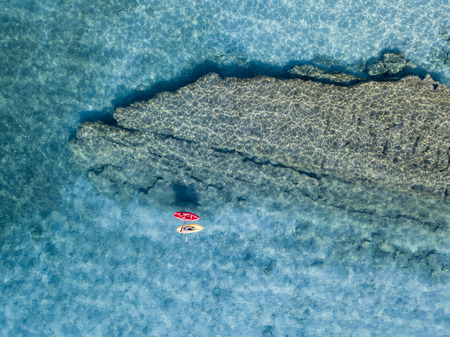 Aerial view of a canoe in the water floating on a transparent sea. Bathers at sea. Zambrone, Calabria, Italy. Diving relaxation and summer vacations. Italian coasts, beaches and rocks.の写真素材