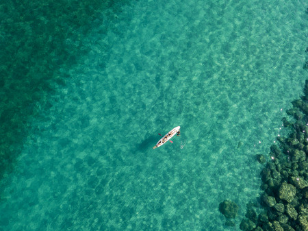 Aerial view of a canoe in the water floating on a transparent sea. Bathers at sea. Zambrone, Calabria, Italy. Diving relaxation and summer vacations. Italian coasts, beaches and rocksの写真素材