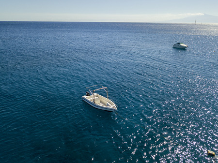 Aerial view of a moored boat floating on a transparent sea. Diving relaxation and summer vacations. Italian coasts, beaches and rocksの写真素材