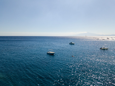 Aerial view of a moored boat floating on a transparent sea. Diving relaxation and summer vacations. Italian coasts, beaches and rocksの写真素材