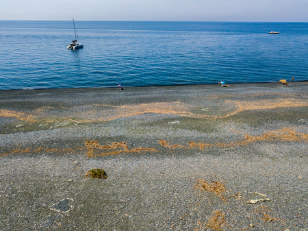 Aerial view of the black pebble beach, Nonza, Geometric designs made with stones, sailboats and moored boats near the beach. Cap Corse Peninsula, Corsica. Coastline. franceの写真素材