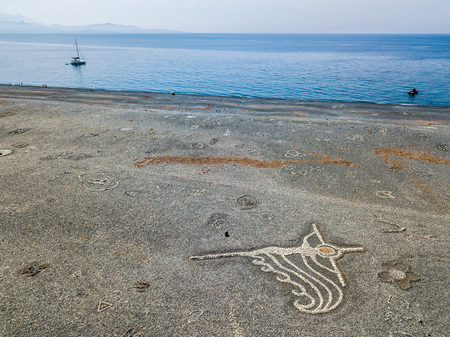 Aerial view of the black pebble beach, Nonza, Geometric designs made with stones, sailboats and moored boats near the beach. Cap Corse Peninsula, Corsica. Coastline. franceの写真素材