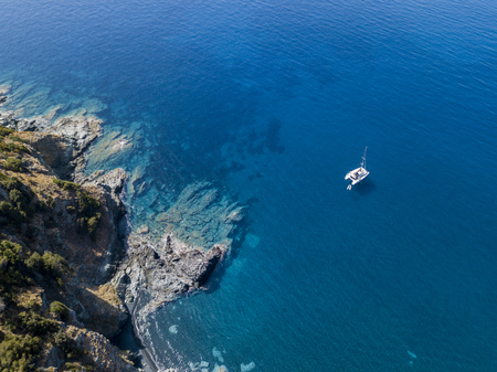 Aerial view of a cliff overlooking the sea and a moored catamaran, boat. Cap Corse Peninsula, Corsica. Coastline. franceの写真素材