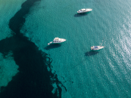 Aerial view of moored boats floating on a transparent sea. Diving relaxation and summer vacations. French Riviera, Corsica. franceの写真素材