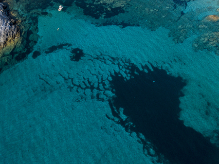 Aerial view of a moored boat floating on a transparent sea. Diving relaxation and summer vacations. French Riviera, Corsica. franceの写真素材