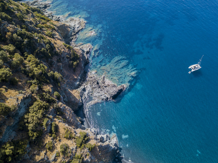 Aerial view of a cliff overlooking the sea and a moored catamaran, boat. Cap Corse Peninsula, Corsica. Coastline. franceの写真素材