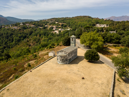 Aerial view of the church of San Michele de Murato, bell tower and aps. Surrounded by a square with trees. Northern Corsica. franceの写真素材