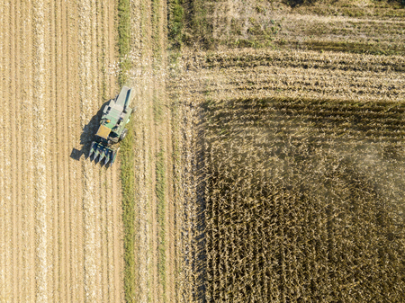 Combine harvesting seed from fields, aerial view of a field with a combine harvester with cornhusker gathering the crop. Agriculture and cultivation, cuttings, corn threshing, fields in the countrysideの写真素材